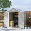 An open garden shed filled with storage items, set in a paved outdoor area with plants and a wooden fence. Produktbild-Vorschau