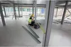 A construction worker is measuring a metal beam on a construction site. Voir les images du produit