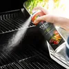 A hand is spraying a grill with a can of cooking spray. Produktbild-Vorschau