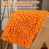 A close-up of an orange chenille mop head resting on a wooden surface. Produktbild-Vorschau