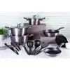 A collection of cookware and utensils arranged on a surface in front of a brick-patterned wall. Podgląd zdjęcia produktu