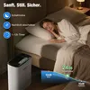 A woman sleeping in a bed next to an air purifier, with feature callouts and noise level graphics. Produktbild-Vorschau