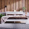 A white bed frame with brown bedding and a beige throw blanket is set against a wooden paneled wall in a bedroom setting. Náhled obrázku produktu