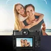 A couple is piggybacking on a beach, with a digital camera in the foreground showing a preview of the couple. Podgląd zdjęcia produktu