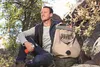 A man sitting outdoors with a backpack and a water bottle. Podgląd zdjęcia produktu