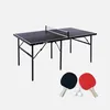 A black ping pong table with a net, two paddles (one black, one red), and three white balls are displayed against a white background. Produktbild-Vorschau