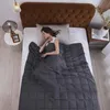 A woman sleeping peacefully under a weighted blanket on a bed. Produktbild-Vorschau