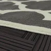 A close-up view of a rug with a geometric pattern, showing the texture and edge of the rug resting on a dark wooden floor. Produktbild-Vorschau