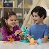 Two children are playing with a Play-Doh dinosaur toy on a table. Náhled obrázku produktu