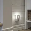 A white night light is plugged into a white paneled wall. Podgląd zdjęcia produktu
