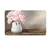 A cute vase with a smiley face holding pink peonies on a wooden shelf, with light rays shining from the top right. Produktbild-Vorschau