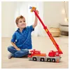 A young boy is playing with a toy fire truck with a crane. Produktbild-Vorschau