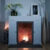A fireplace surround with a fire burning inside, decorated with flowers and vases. Náhled obrázku produktu