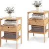 Two identical bamboo nightstands are shown against a white background. Each nightstand has a top surface with a vase of flowers and a cup of coffee, a shelf with books, a drawer, and a storage box on the bottom shelf. Podgląd zdjęcia produktu