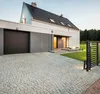 A modern house with a garage and a driveway, featuring a black LED outdoor spotlight. Náhľad obrázku produktu