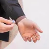 A person is adjusting a pink watch band on their wrist. Produktbild-Vorschau