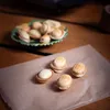Four nut-shaped cookies are arranged on brown paper, with a plate of more cookies in the background. Náhľad obrázku produktu