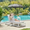 A woman relaxing on a lounge chair under a patio umbrella next to a swimming pool. Produktbild-Vorschau