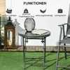 A small round table with a book and a decorative lantern on it, placed on a green lawn next to a wooden lantern and a chair. Produktbild-Vorschau
