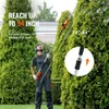 A man is using a telescopic hedge trimmer to trim a tall green hedge. Náhled obrázku produktu