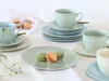 A table setting with teacups, saucers, plates, and macarons. Náhľad obrázku produktu