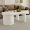 A white oval coffee table with two drawers sits in front of a brown sectional sofa in a living room. Voir les images du produit