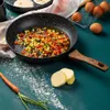 A frying pan with chopped vegetables cooking in it, along with ingredients like eggs, butter, and a carrot on a teal surface. Náhľad obrázku produktu