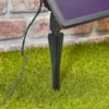 A close-up view of a solar panel stake inserted into grass, with a brick wall in the background. Produktbild-Vorschau