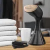 A handheld garment steamer with accessories and towels on a wooden table. Podgląd zdjęcia produktu