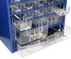 A close-up, angled view of a blue metal storage cabinet with multiple clear plastic drawers filled with various small items like screws, nuts, and other hardware. Produktbild-Vorschau