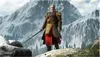 A man in armor stands on a rocky outcrop with a sword in hand, with a snowy mountain range in the background. Podgląd zdjęcia produktu