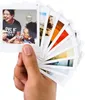 A hand holding a fan of Fujifilm Instax Square film photos. Voir les images du produit