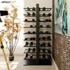 A modern wine rack filled with wine bottles, placed in a room with a plant and artwork. Podgląd zdjęcia produktu