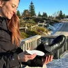 A woman holding a shoe insert next to a boot outdoors in a snowy environment. Voir les images du produit