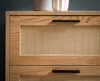 A close-up view of a wooden dresser with rattan inserts and black handles. Produktbild-Vorschau