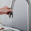 A hand is holding a kitchen faucet sprayer, and water is spraying out. Podgląd zdjęcia produktu