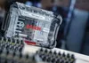 A close-up shot of a Bosch impact driver bit set case, with other tools blurred in the background. Náhled obrázku produktu