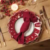 A festive Christmas table setting with plates, cutlery, a candle, and berries. Produktbild-Vorschau