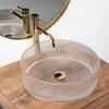 A clear glass vessel sink with a gold drain and faucet, placed on a wooden countertop. Anteprima dell’immagine prodotto