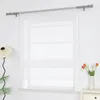 A white sheer Roman blind hangs on a window, with a lamp and plants on the left and a vase of tulips on the right. Produktbild-Vorschau