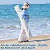 A person walks on a beach carrying a rolled-up item. Produktbild-Vorschau