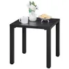 A black metal side table with a white mug, a vase with flowers, and a bowl of cookies on top. Produktbild-Vorschau
