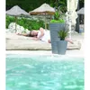 A woman is lying on a beach next to two decorative planters. Náhľad obrázku produktu
