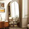 A full-length arched mirror is placed in a room next to a wooden dresser and an armchair. Anteprima dell’immagine prodotto