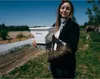 A woman is sowing seeds in a field using a seed spreader. Produktbild-Vorschau