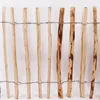 A close-up view of a wooden picket fence made of hazel branches, secured by wire. Voir les images du produit