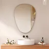 A modern bathroom vanity with a sink, faucet, and an asymmetrical mirror above it. Produktbild-Vorschau