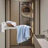 A laundry room with a stacked washer and dryer, a wall-mounted ironing board with laundry on it, and a sink. Produktbild-Vorschau