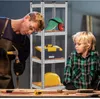 A father and son are in a workshop, with a storage rack filled with tools and safety equipment. Anteprima dell’immagine prodotto