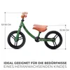 A green balance bike with brown and pink accents, shown against a white background with measurement indicators. Produktbild-Vorschau